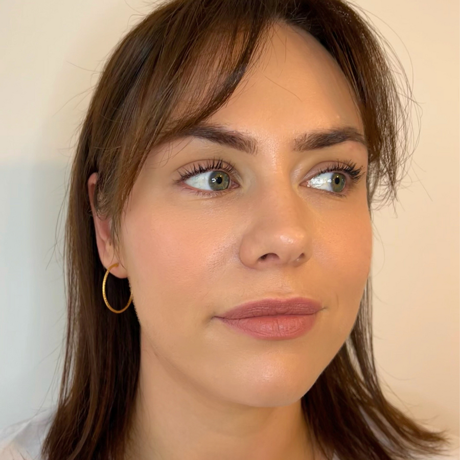 A close-up image of a person wearing large 22 karat gold hoop earrings.